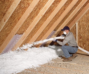 Installing fiberglass blown-in insulation in attic